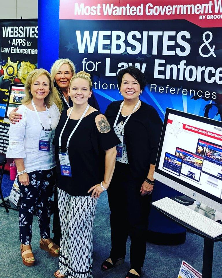 Group photo of Renea Adams, Angela Webb Bertel Sr., Emily Dillner and Shannon Brooks before their booth at the Nation Sheriffs Conference