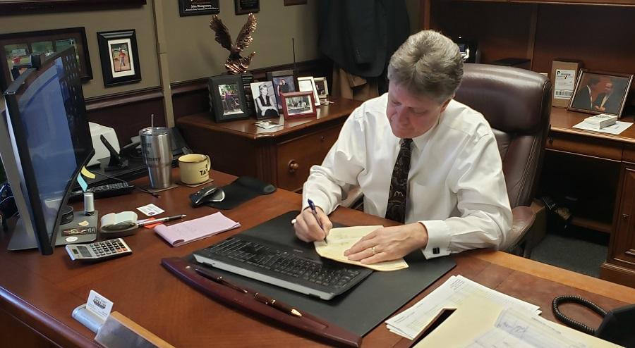 John Montgomery signing restitution check at his desk