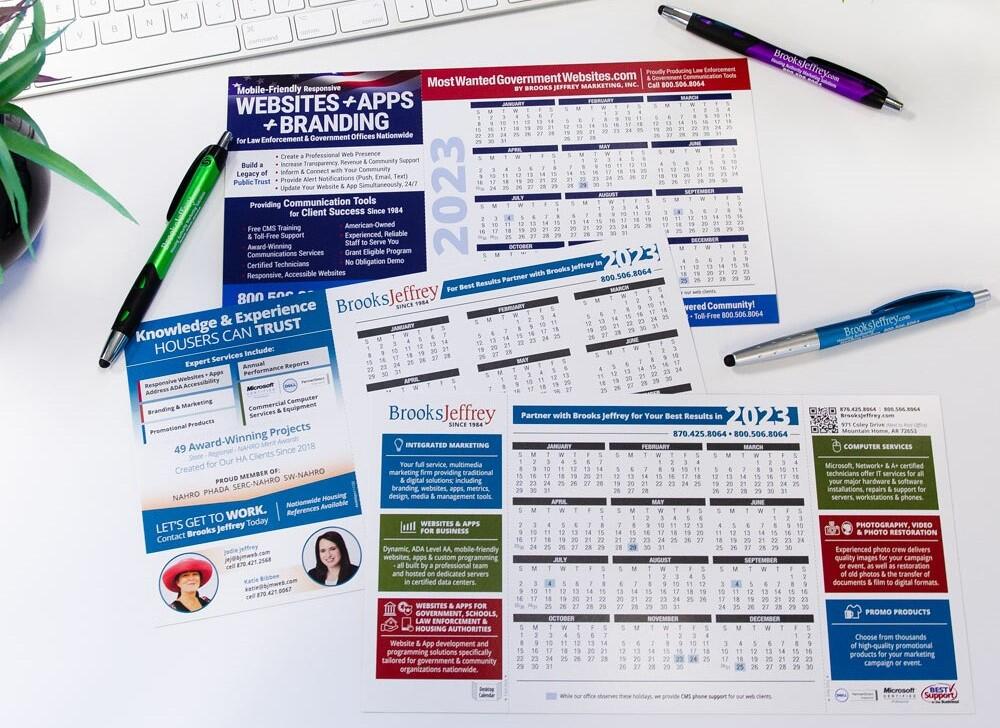 Three 2023 Calendars surrounded by pens, plants, and a keyboard.